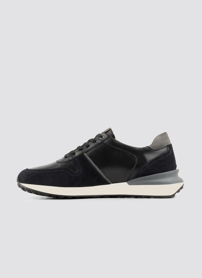 Black and grey men's leather sneaker with suede panels and white sole on light background 
