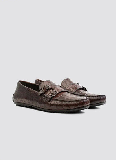 Brown crocodile pattern leather loafers with buckle detail for men on white background 