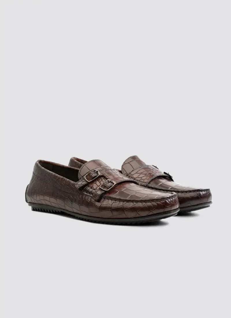 Brown crocodile pattern leather loafers with buckle detail for men on white background 