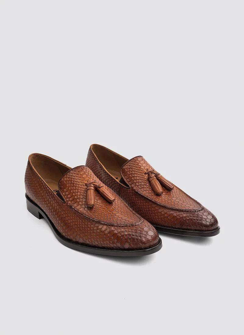 Men's tan textured leather tassel loafers with pointed toes on a plain background 
