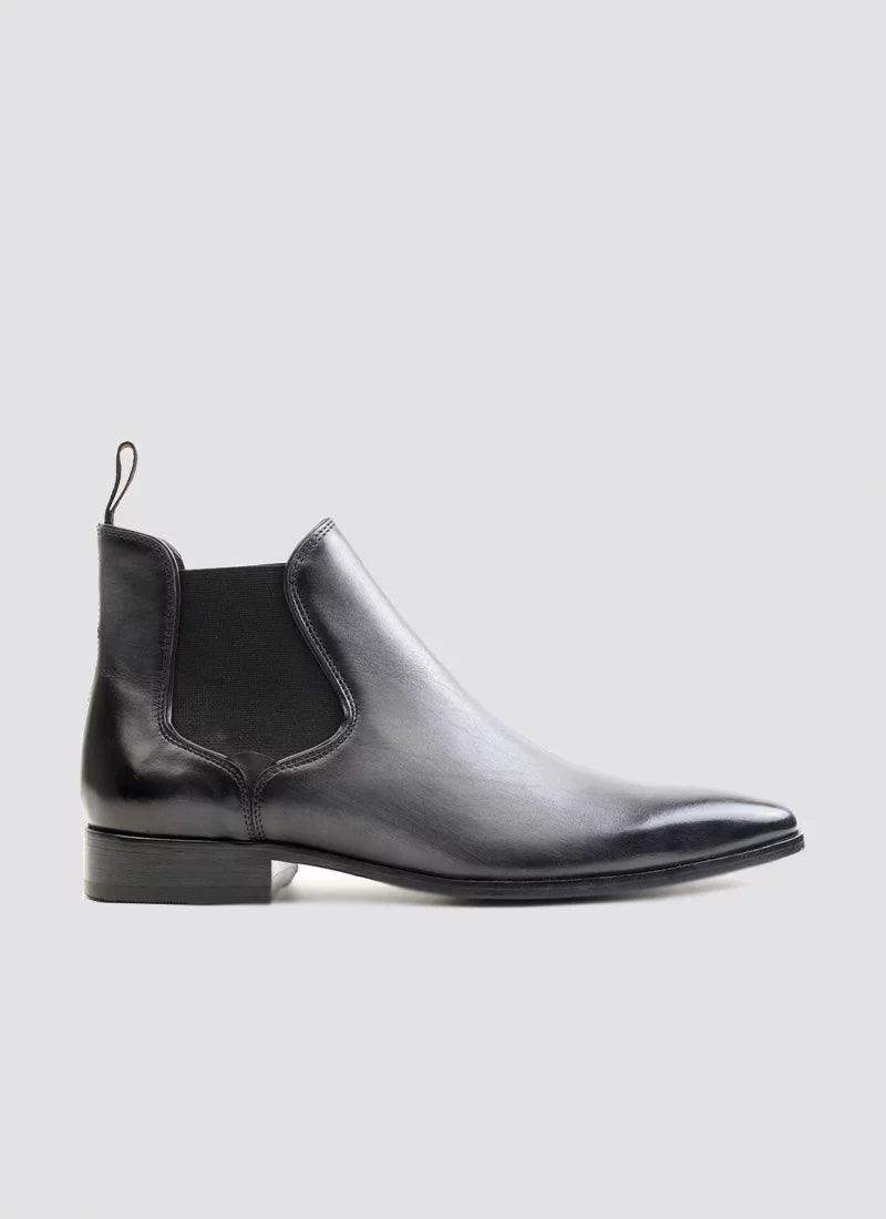 Men's black leather Chelsea boot with elastic side panel, low heel, and pull tab on a white background 