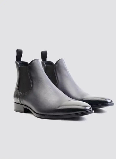 Men's black leather Chelsea boots with elastic side panels on a light background 