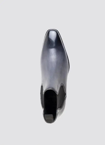 Top view of a grey leather chelsea boot with a pointed toe on a plain background 