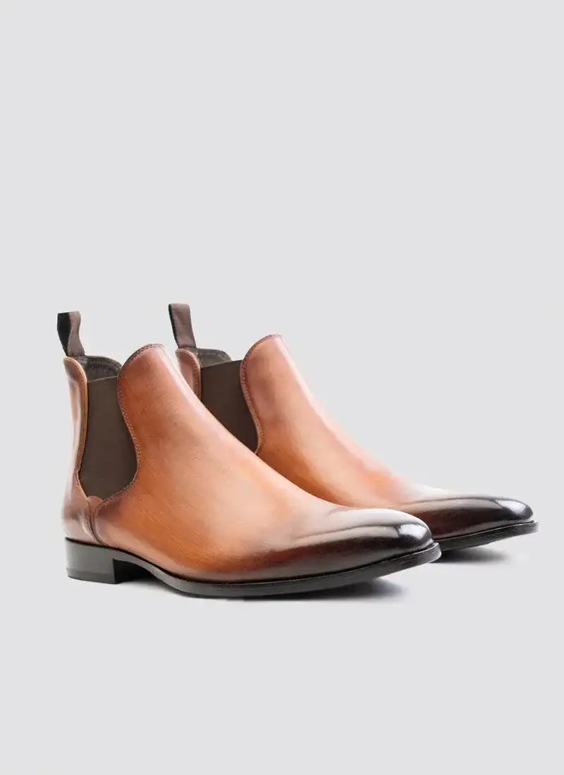 Tan leather Chelsea boots for men with dark brown toe, pull tabs, and elastic side panels. 
