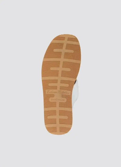 Close-up of tan rubber sole on white handmade loafer with textured grip pattern 