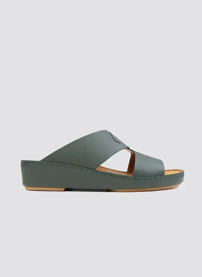 Green leather slide sandal with wedge heel and cross-strap design on white background 
