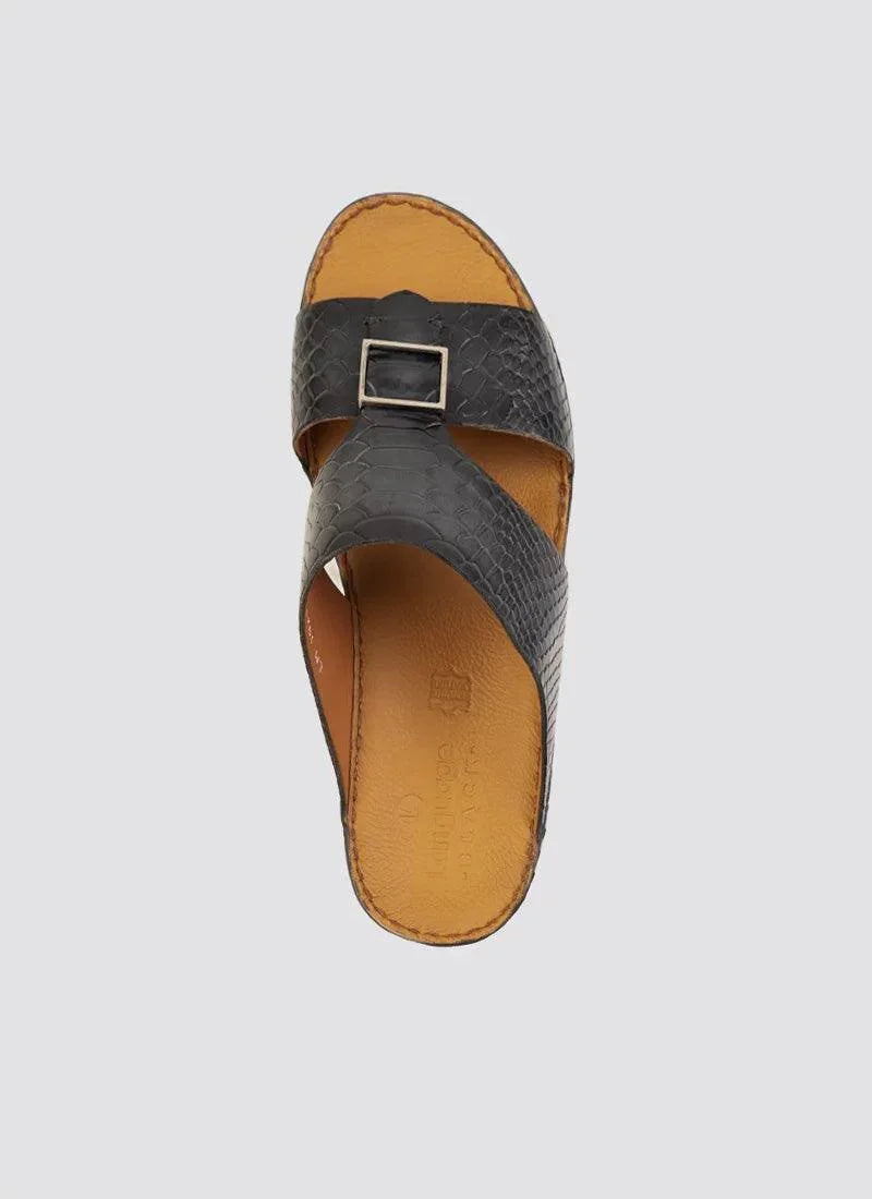 Men's black textured leather slide sandal with cross straps and silver buckle on tan footbed
