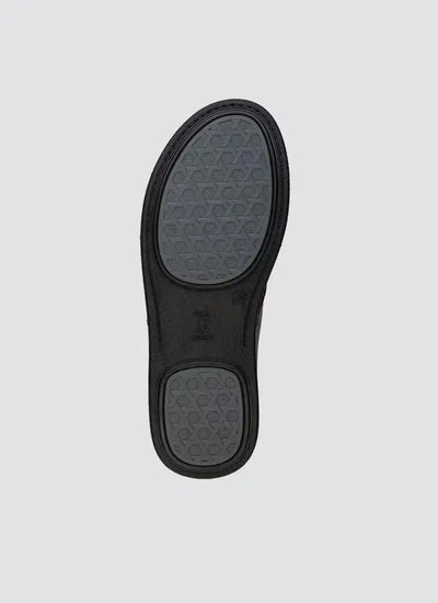 Black shoe sole with textured grip pattern on a plain background 