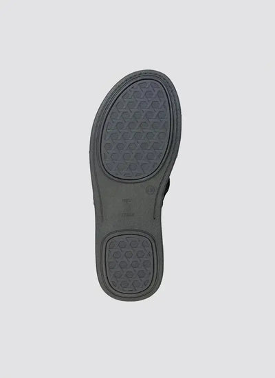 Close-up of black shoe sole with geometric grip pattern on light grey background 