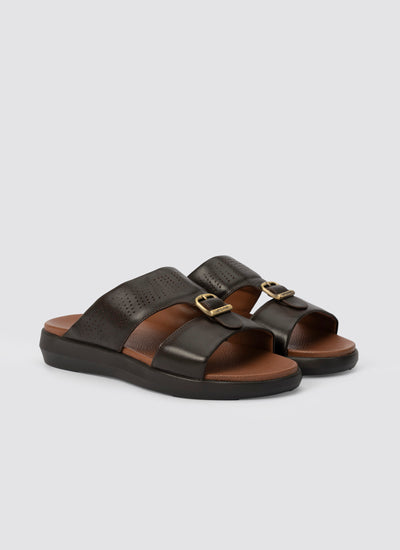 Pair of brown sandals with gold buckles on a light gray background 