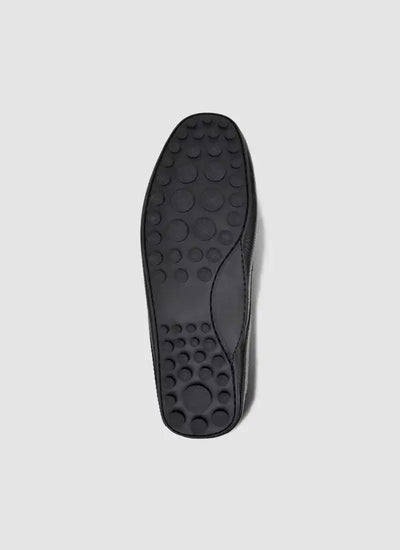 Black shoe sole with textured circular grip pattern, photographed on a light background 