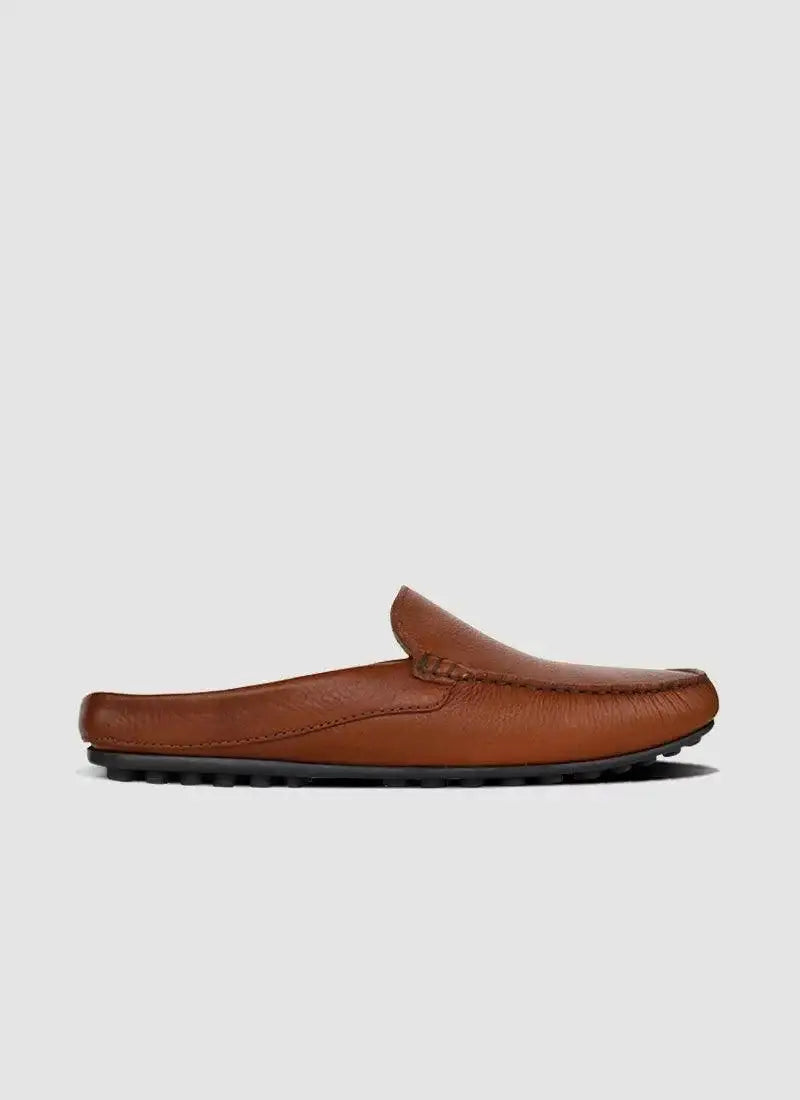 Tan leather men's loafer mule with textured sole on plain background 