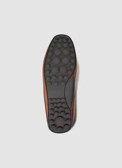 Close-up of brown leather loafer shoe sole with rubber grip and textured pattern. 