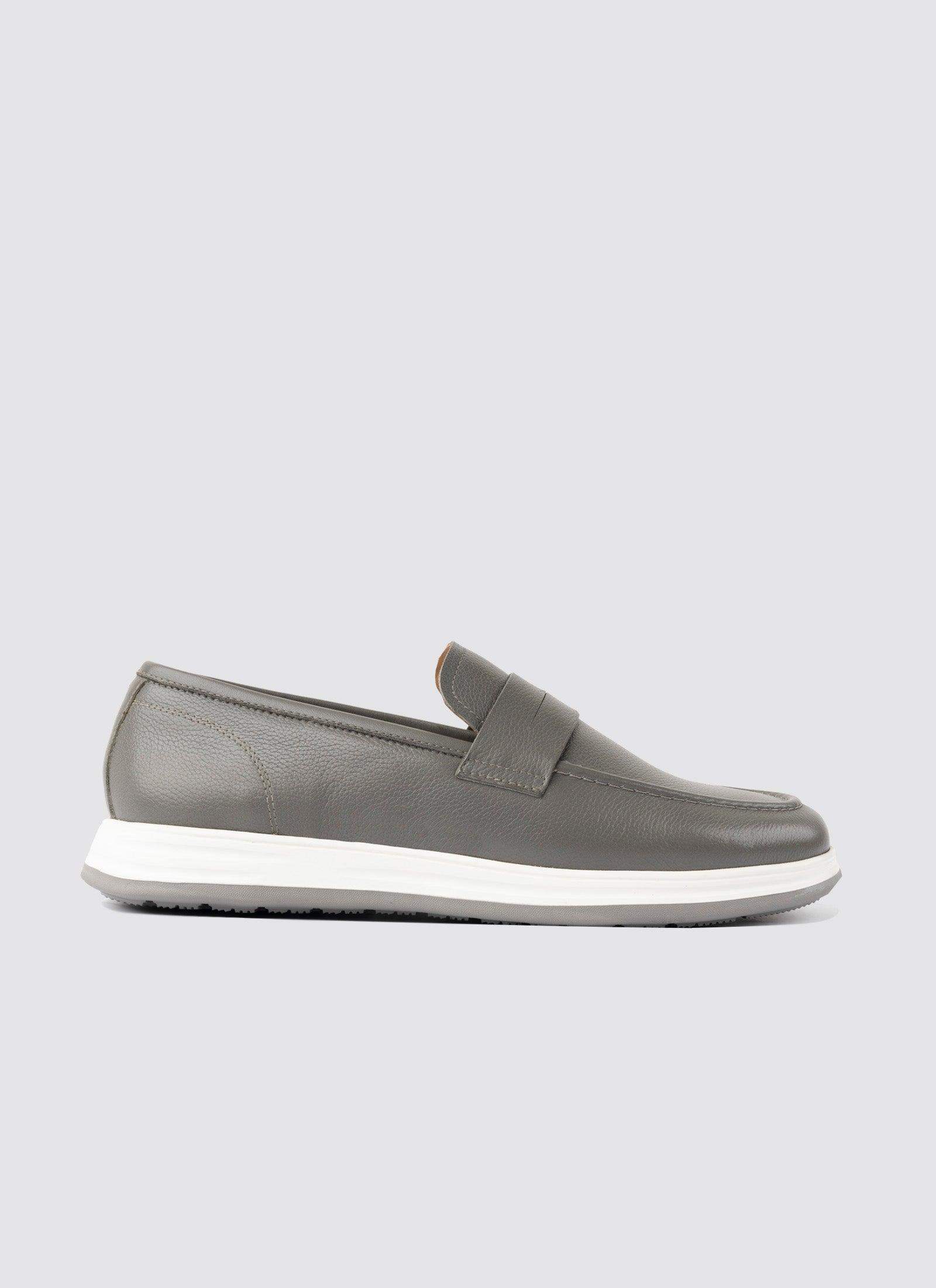 Men's grey leather loafer with white sole on plain background, casual footwear 