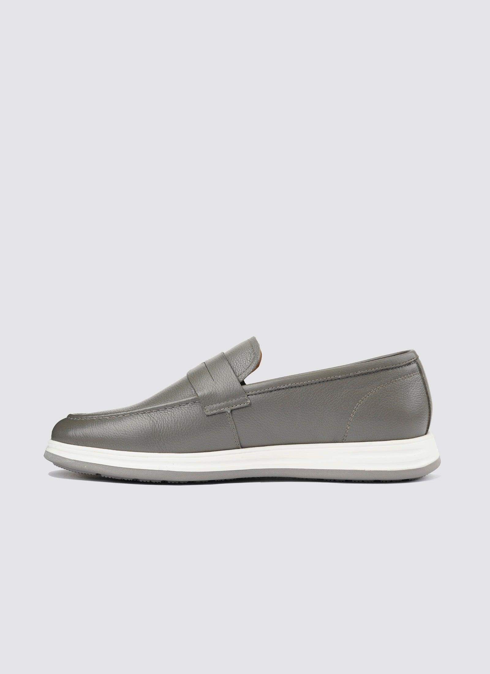 Men's grey leather loafer with white rubber sole, casual slip-on shoe against plain background 