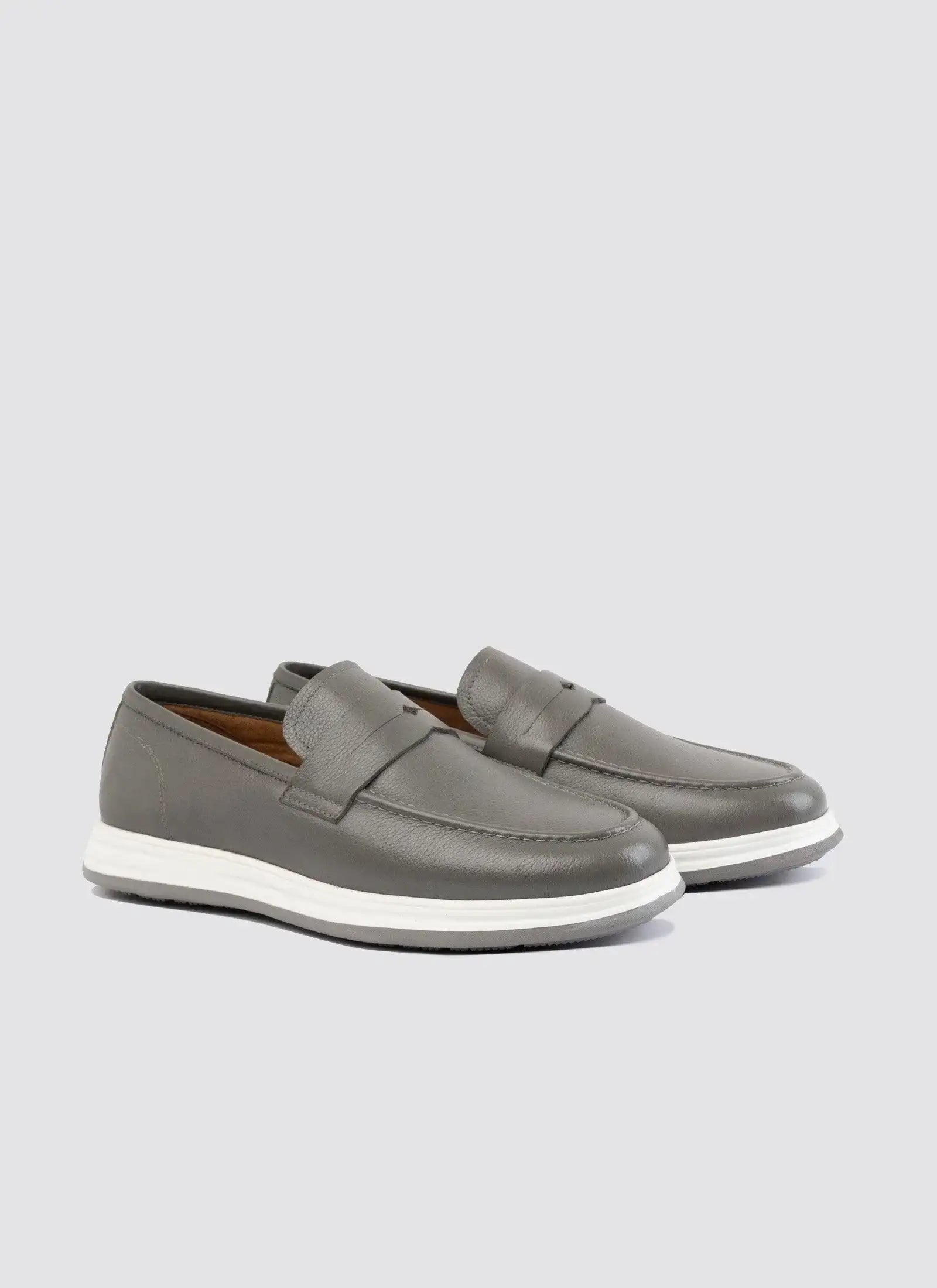 Grey leather loafers with white rubber soles for men, displayed on a plain background. 
