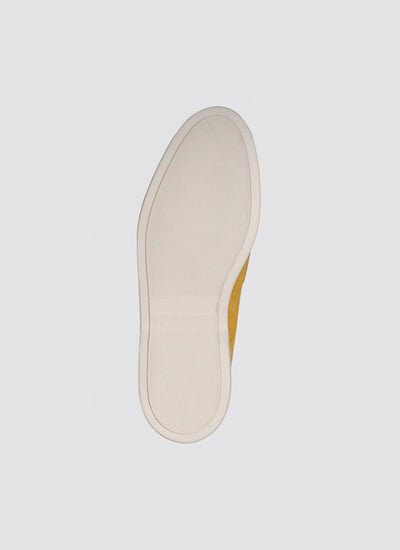 Mustard yellow shoe with textured white sole, viewed from the bottom on a plain background  