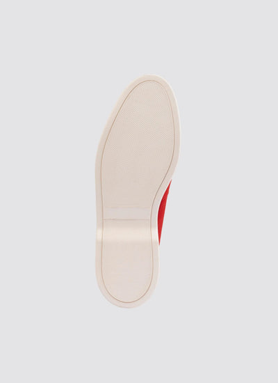 Close-up of red sneaker sole with textured white rubber outsole on light background 