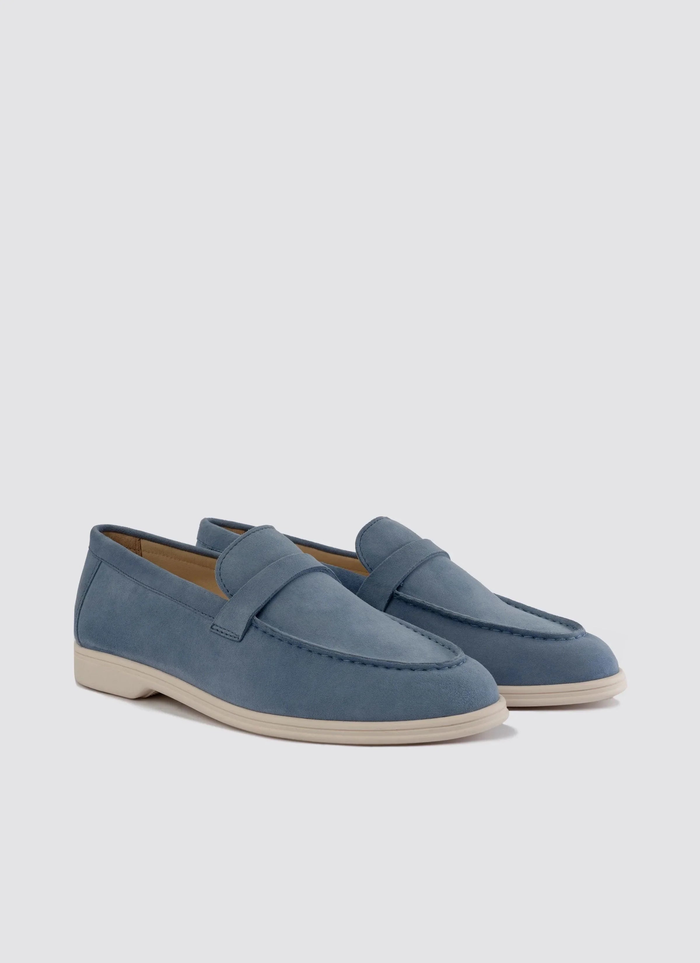Men's light blue suede loafers with white soles on a plain background 