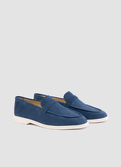 Men's navy blue suede loafers with white soles on a plain background 