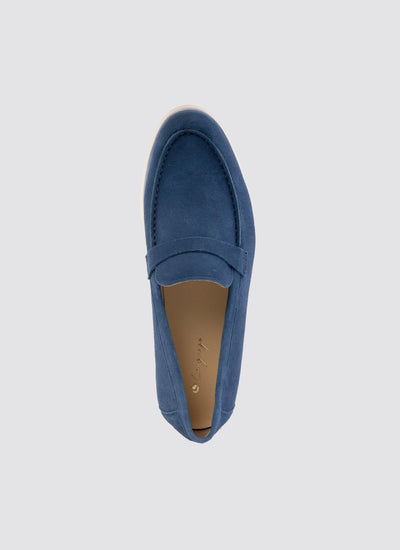 Top view of a navy blue suede loafer shoe with white sole, casual footwear on grey background. 