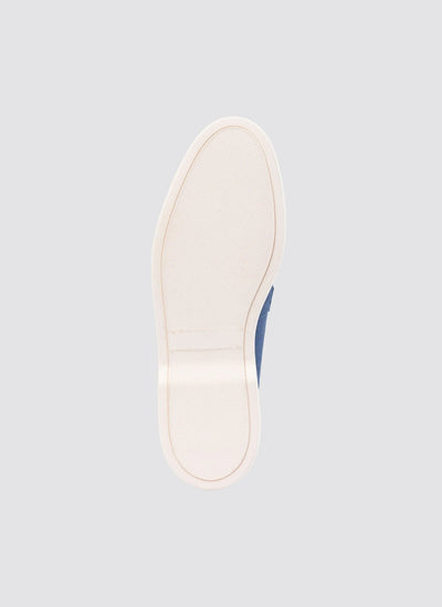 Close-up of rubber sole of a navy blue casual shoe on light grey background 