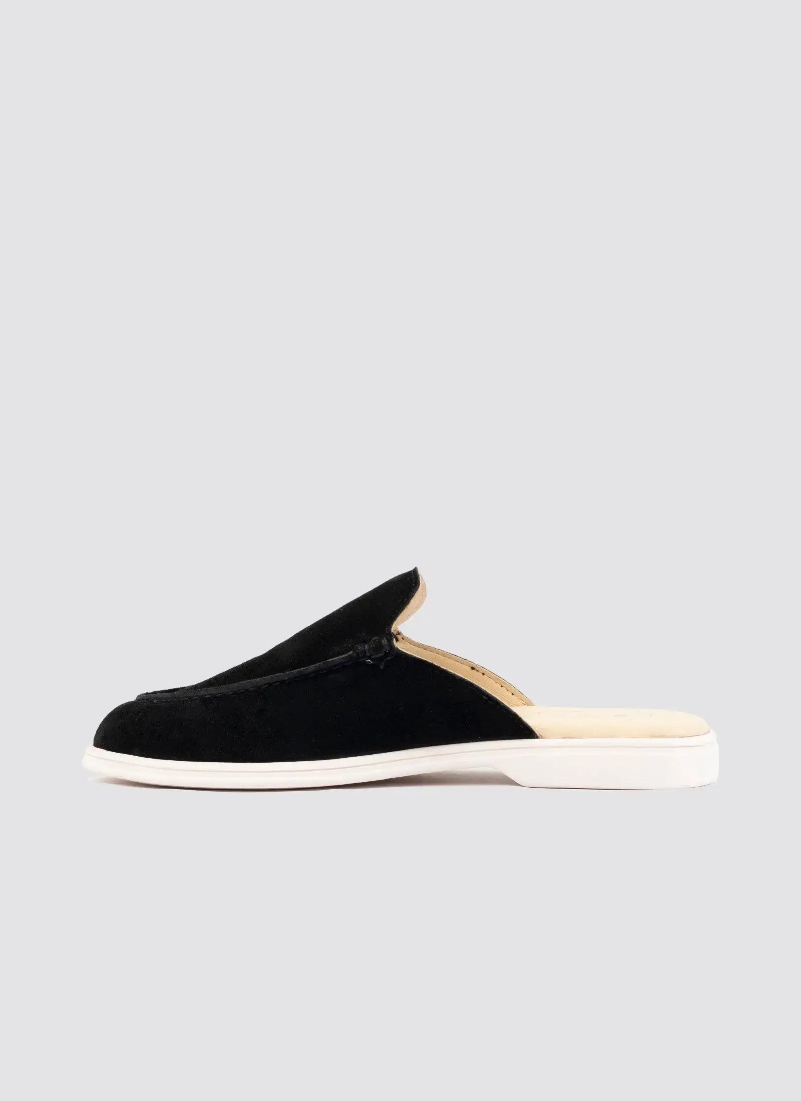 Black suede slip-on loafer with white sole for men, side view on plain background 