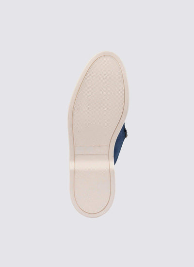 Close-up of cream rubber sole on a navy casual shoe against light background  