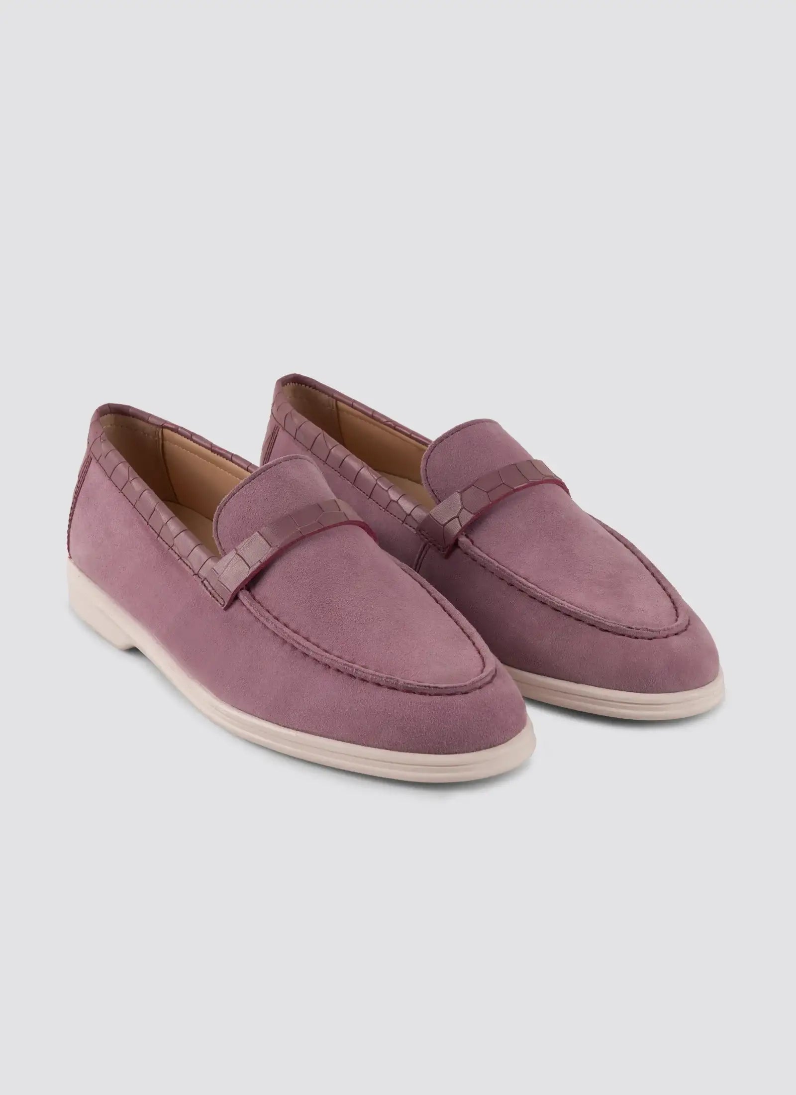 Pair of mauve loafers on a light gray background 