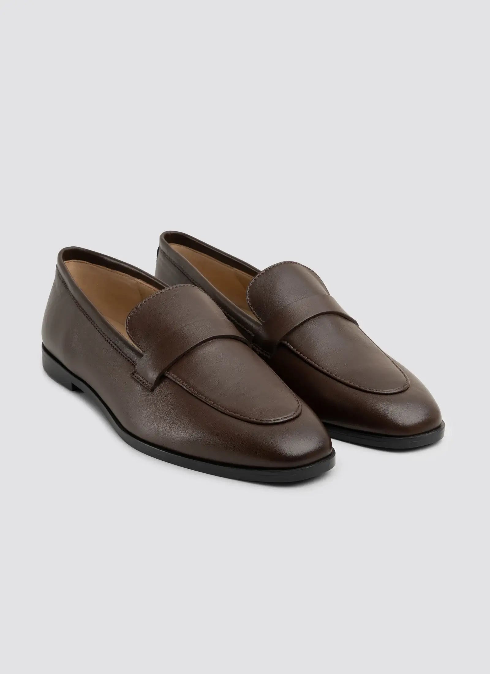Pair of brown loafers on a light gray background 