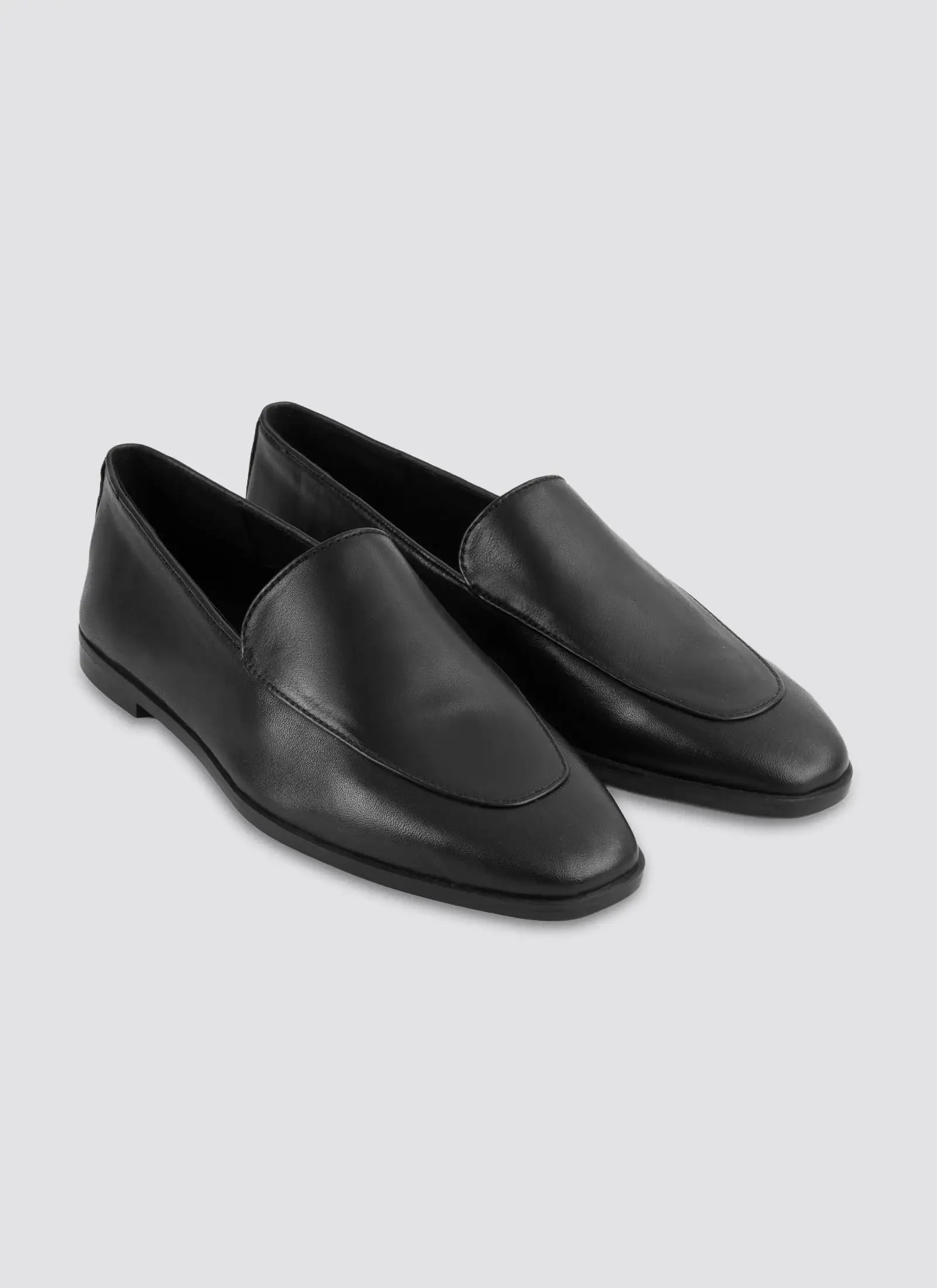 Pair of black loafers on a light gray background 