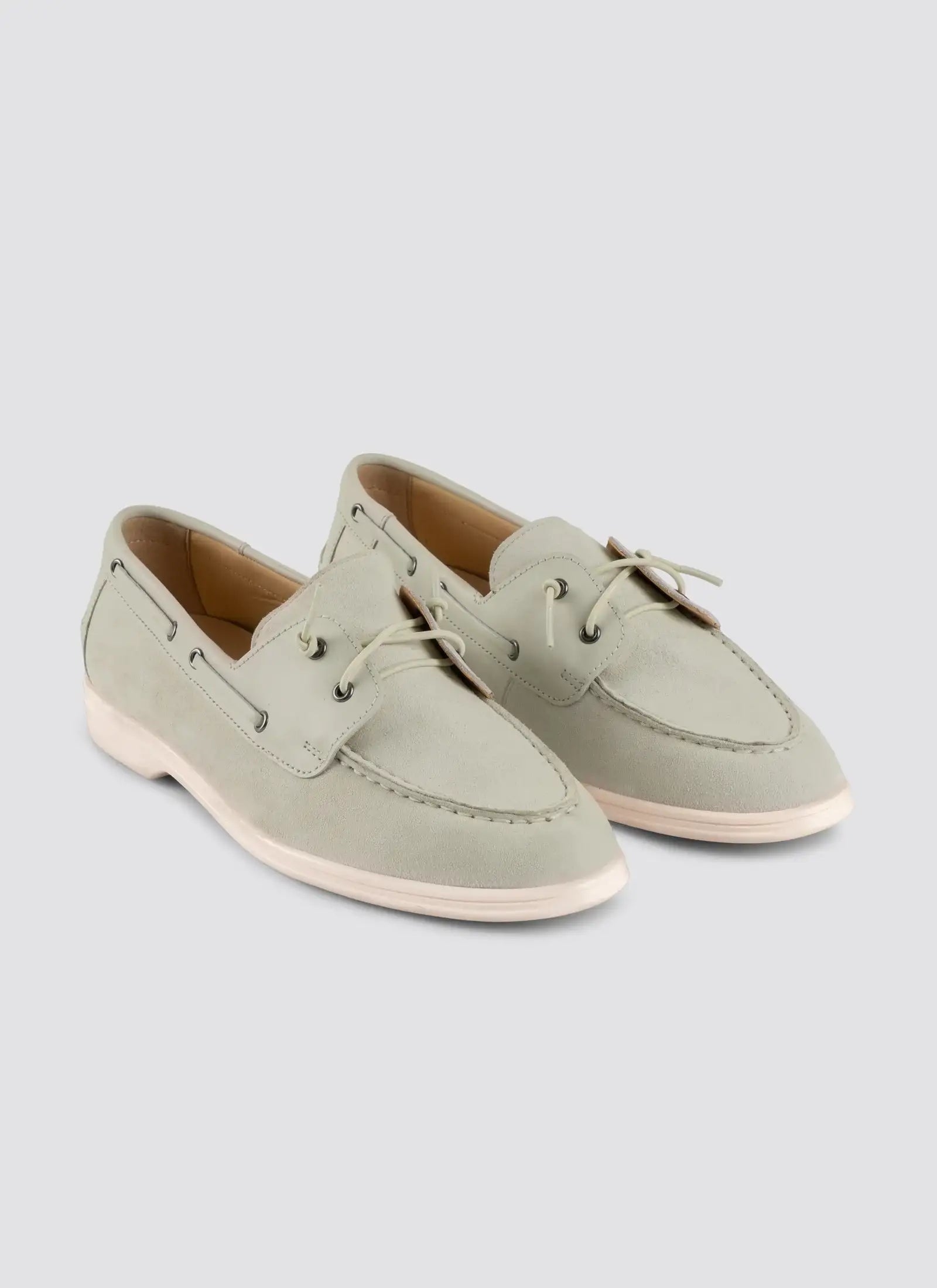 Pair of light green loafers on a light gray background 