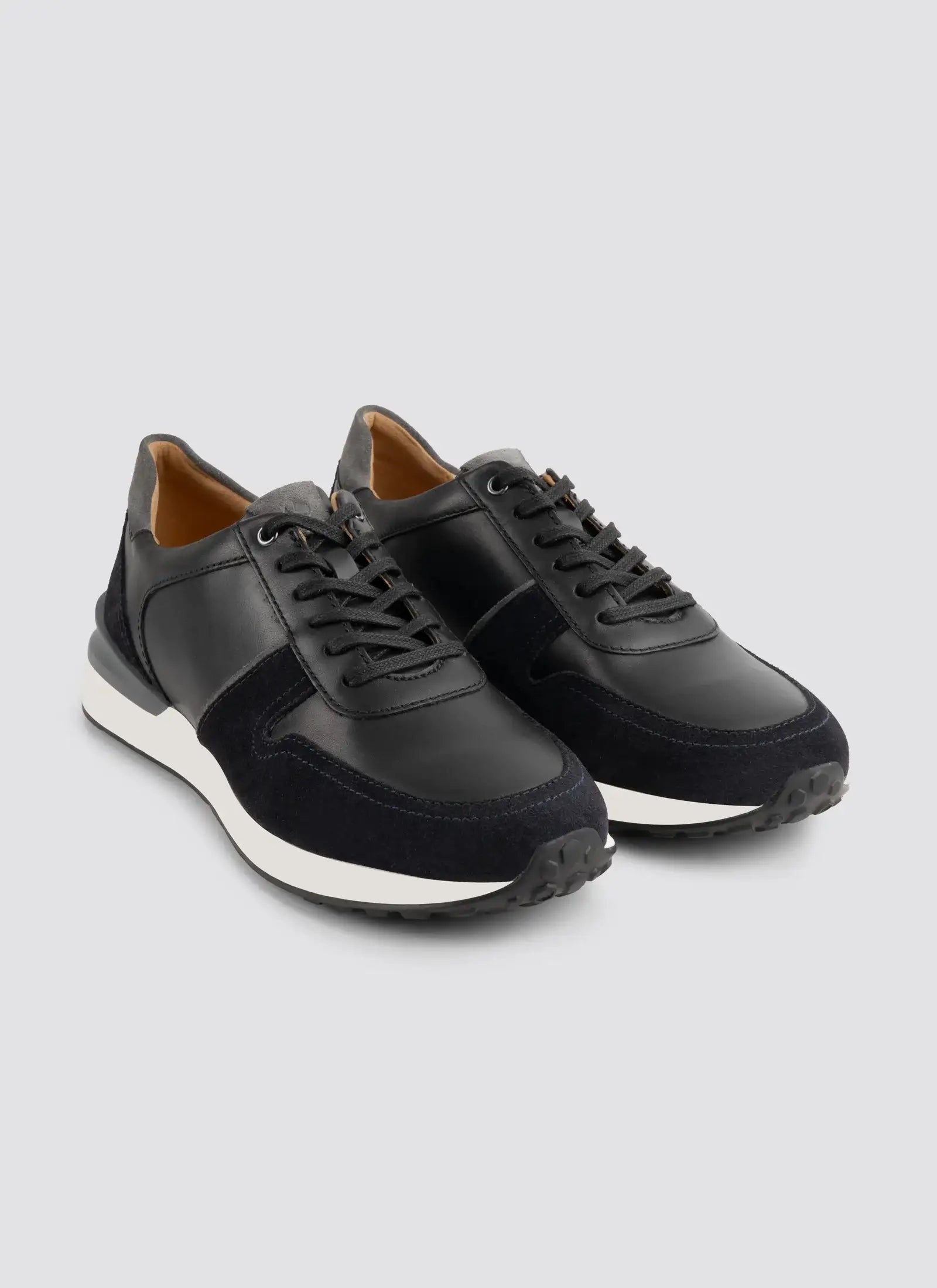 Men's black leather and suede lace-up sneakers with white soles on a light background 