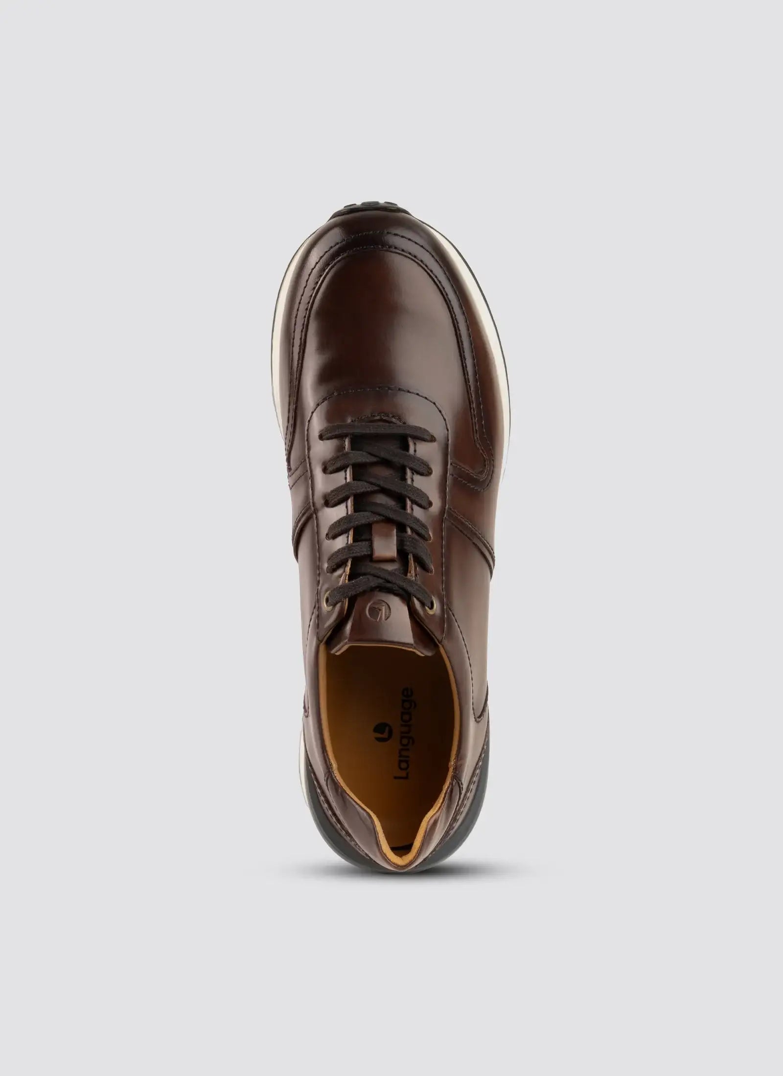 Top view of a brown leather lace-up sneaker with white sole on a plain background  