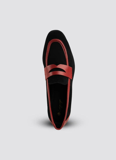 Black loafer with red interior on a light gray background  